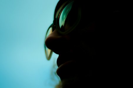 close up photo of person wearing glasses with teal background