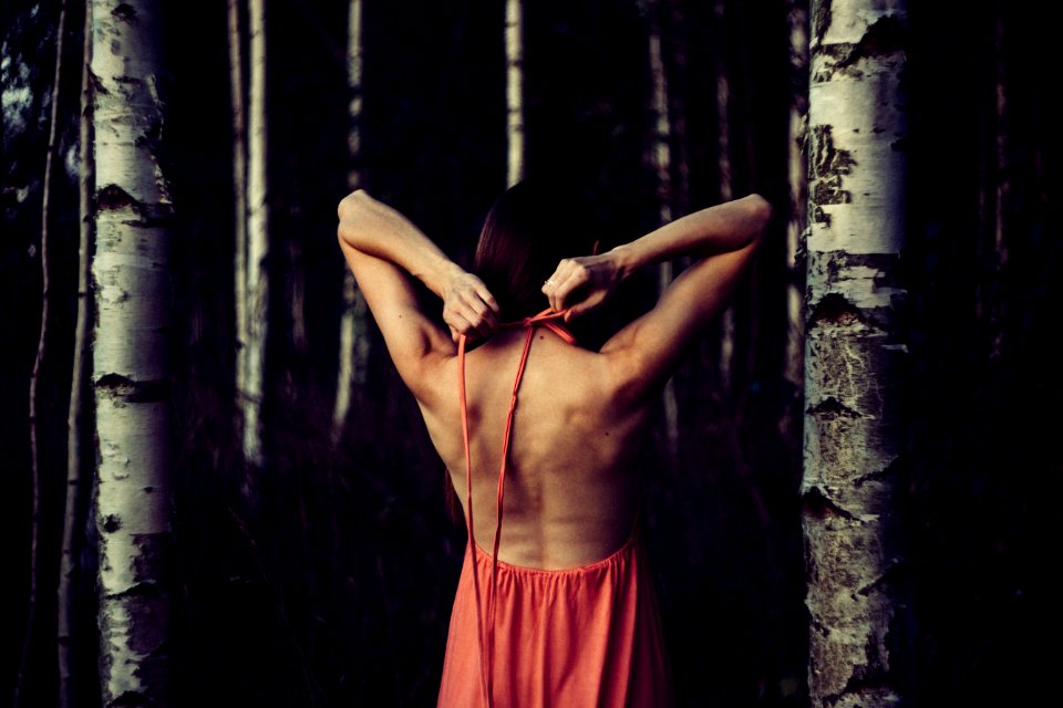 A girl stretching with her arms behind her back inside a forest.