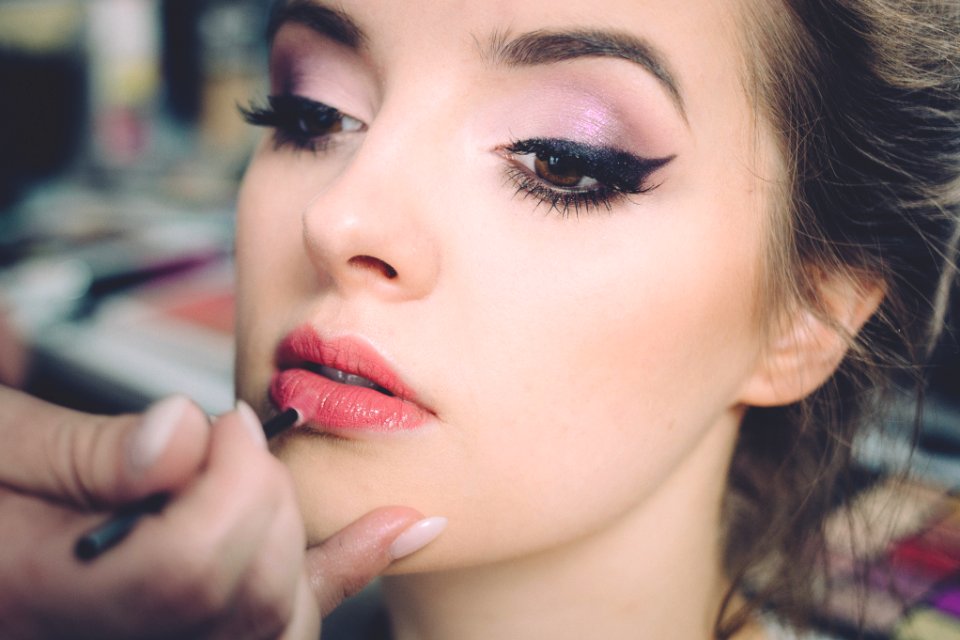 woman getting lips applied with lipstick photo