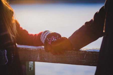 On a winter's day, young lovers hands touch on a cabin railing photo