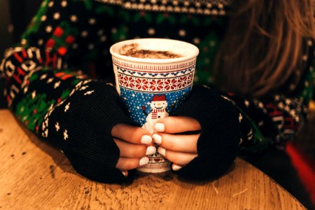 A long-haired woman with white painted nails holding a cup of hot chocolate. photo