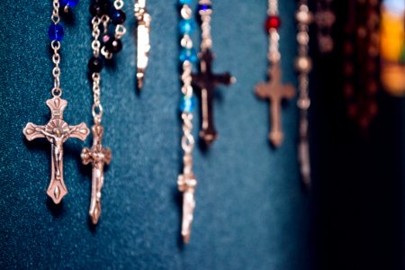 Cross pendants on gem necklaces hanging down a wall.