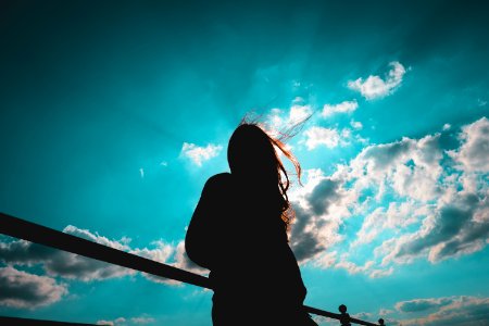 silhouette of woman standing with cloudy sky photo