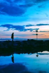 silhouette of person walking on rocks near body of water