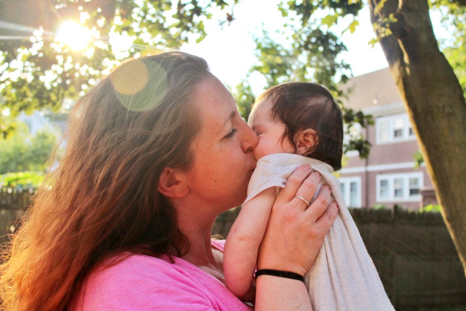A woman kissing an infant on the cheek.