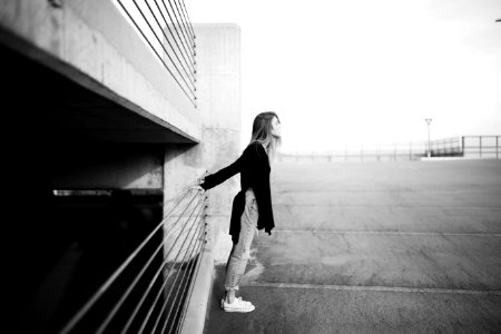 grayscale photography of woman standing near building photo