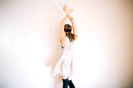 woman wearing white sleeveless top with hands above head
