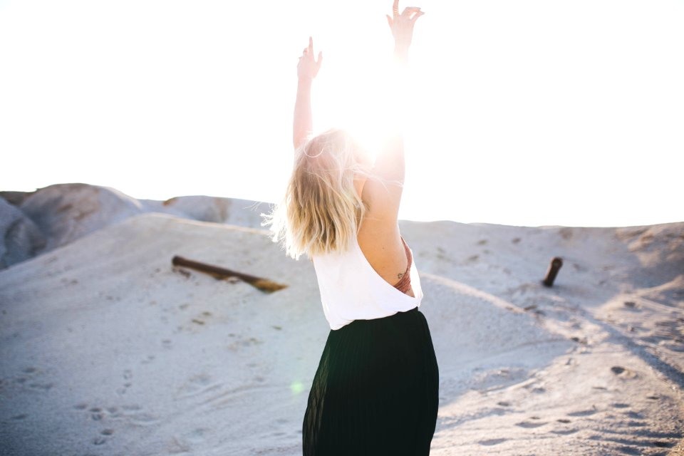 woman standing on the desert while her hands up