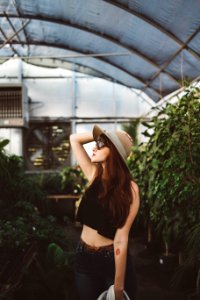 shallow focus photography of woman posing while holding her hat at the garden photo