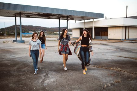 four girls walking near warehouse during daytime photo