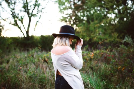 woman in white off shoulder long sleeved top holding black hat photo