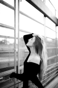 woman wearing off-shoulder top posing beside steel gate in grayscale photography photo