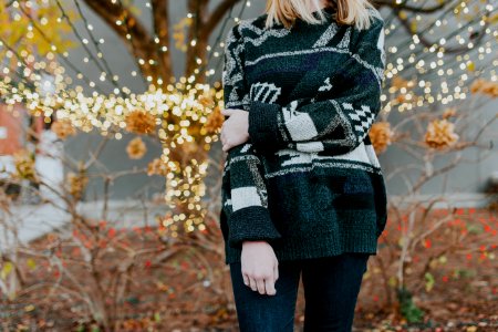 woman wearing sweater standing in front of plants and tree photo