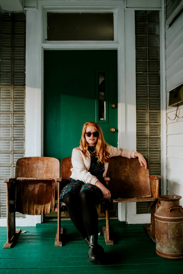 woman in blue dress sitting on brown wooden gang chair during daytime