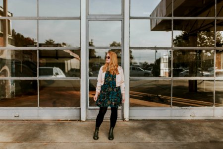 woman wearing pink bolero and black leggings standing in front of glass wall photo