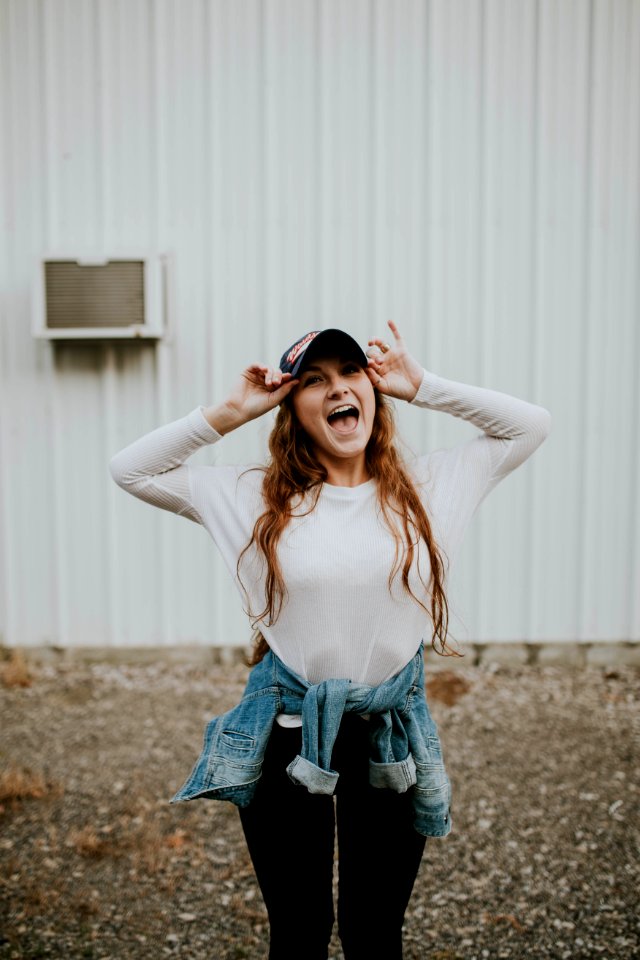 woman wearing black cap standing outside the house while laughing