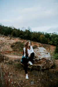 woman sitting on stone boulder outdoor photo