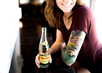 candid photography of woman holding bottle with broad smile photo