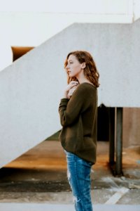 woman wearing brown sweatshirt and whiskered distressed blue jeans