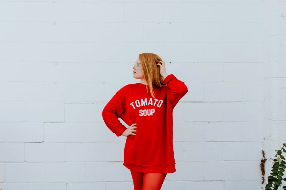woman wearing red long-sleeved shirt standing near white painted wall