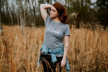 shallow focus photography of woman in gray crew-neck shirt standing in the middle of brown grass field during daytime photo