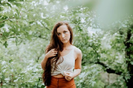 selective focus photography of woman in tank top standing in forest photo