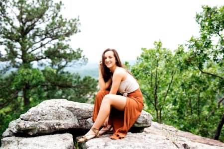 woman sitting on gray rock