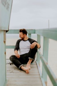 man smiling while sitting on floor during daytime photo