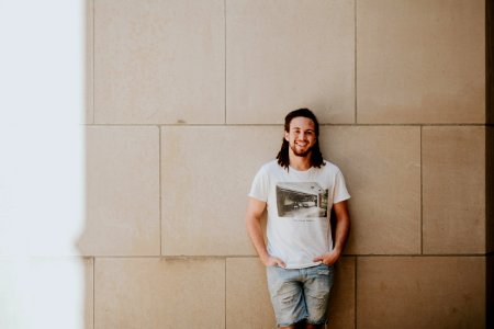 man leaning on white wall photo