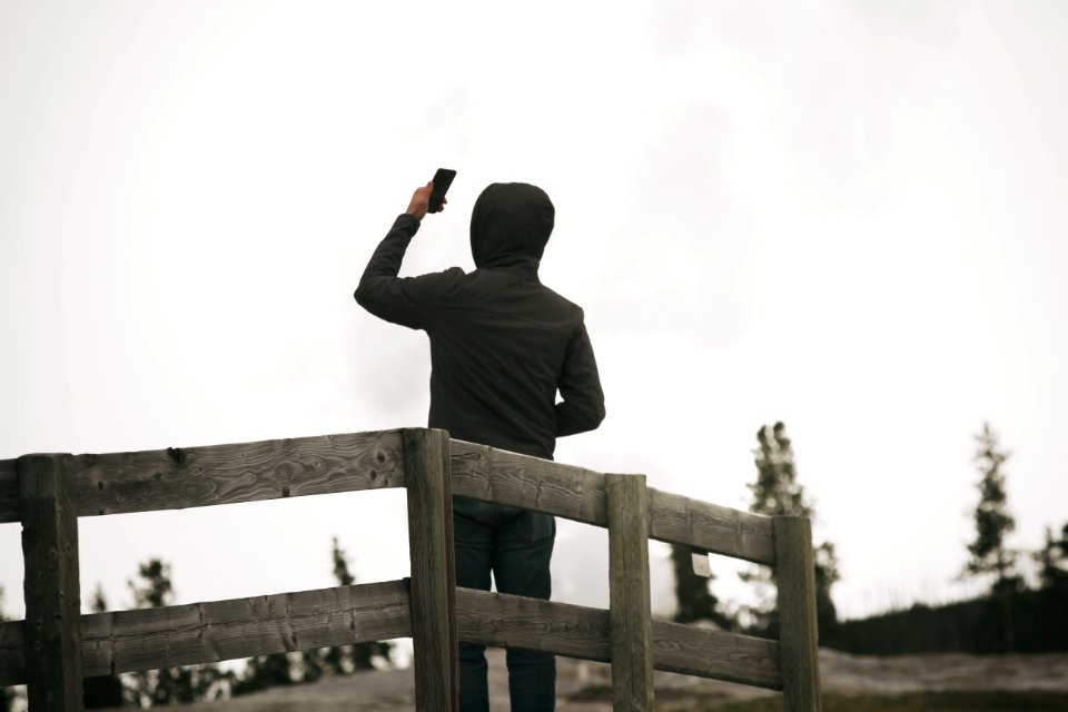 person wearing hoodie holding smartphone