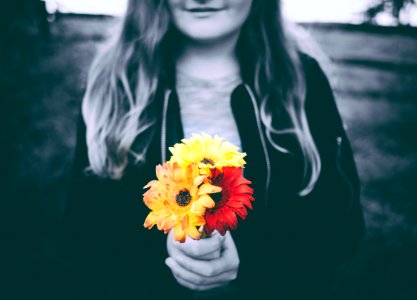 selective-color photo of person holding yellow and red flowers