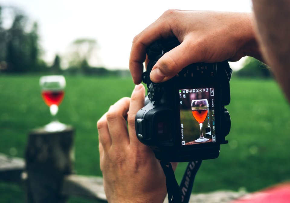 person taking photo of wine goblet