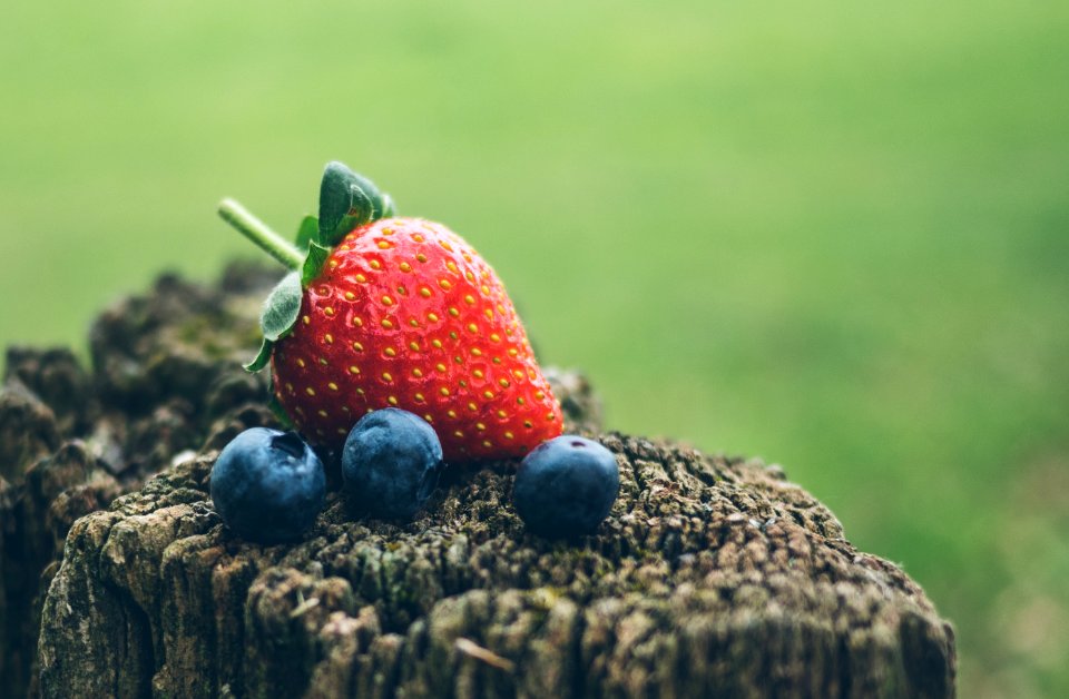 strawberry and three blueberries in closeup photography