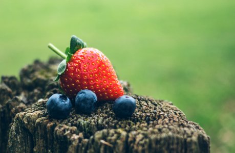 strawberry and three blueberries in closeup photography photo