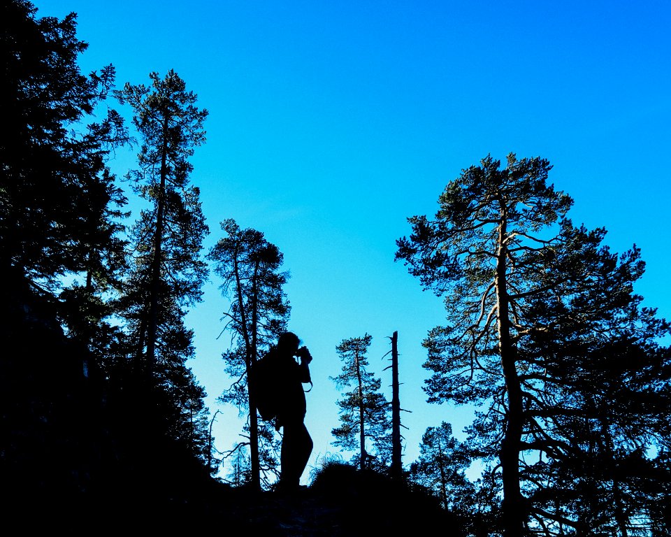 man standing on rock formation under blue sky during daytime photo