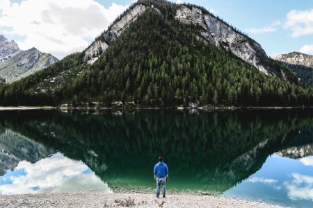 man standing nearby sea fronting green mountain photo