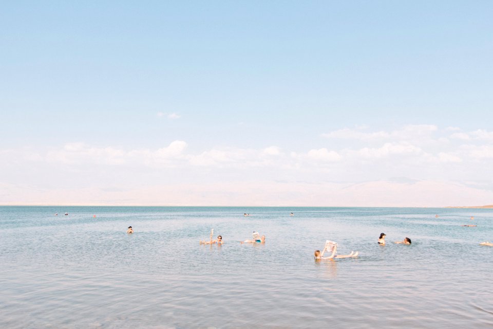 people swimming on sea under cloudy sky