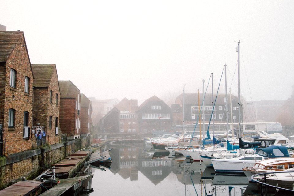 boats on harbour surrounded by fogs during daytime