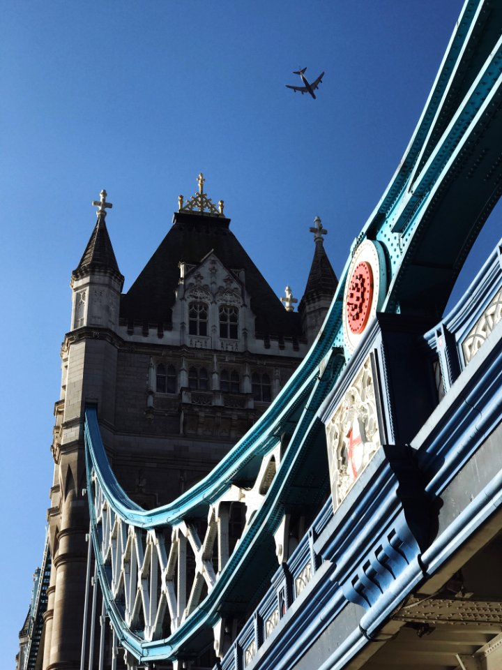 white jetliner flying over Tower Bridge