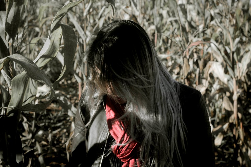 grayscale photo of woman standing beside corn field