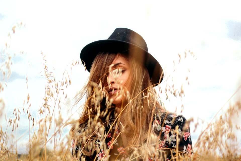 woman wearing black hat near brown grass during daytime