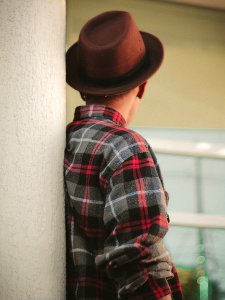 person wearing red, black, and white plaid shirt and brown hat