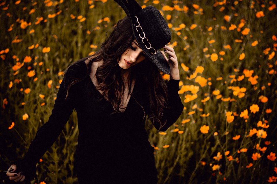 woman holding hat surrounding yellow petaled flowers photo