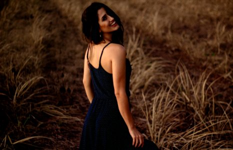 selective focus photography of woman in black dress standing at grass field photo