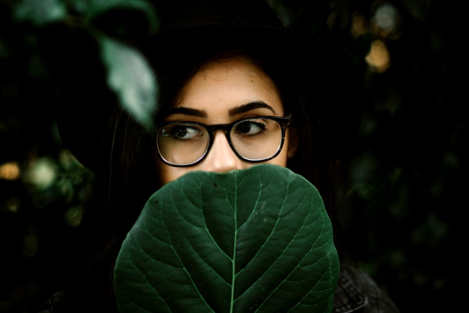 woman covering her mouth with green leaf