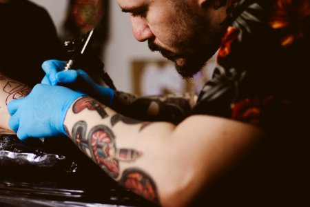 man doing tattoo on person's arm photo