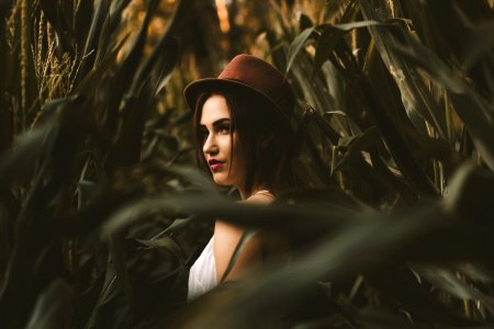 woman in white shirt with hat standing on corn field photo