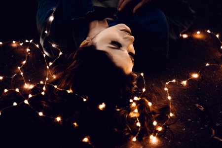 woman lying on yellow string lights photo