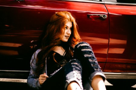 smiling woman sitting beside red car photo