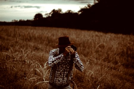 man on grass field using DSLR camera photo